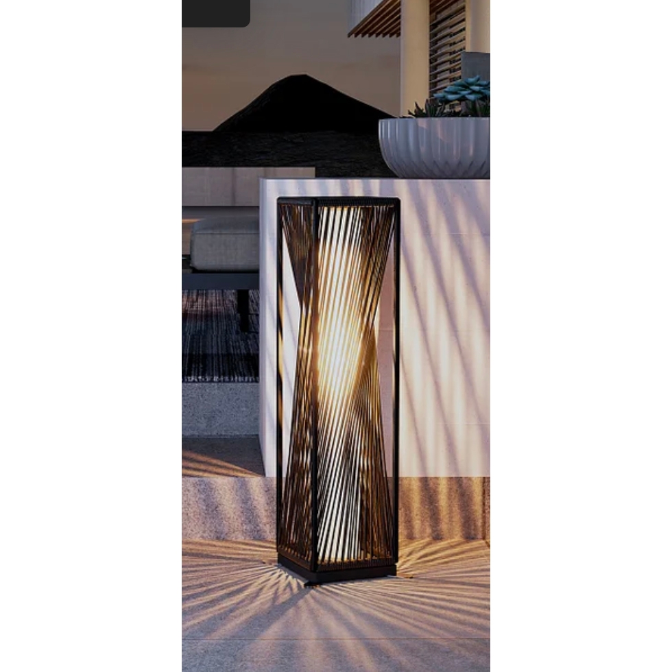 Tall, vertical floor lamp with illuminated slats creating a warm, patterned light effect in a modern room setting.