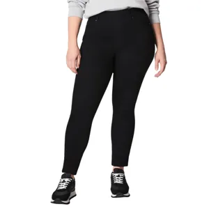 A person wearing black skinny jeans and black sneakers with white laces, paired with a light gray long-sleeve top.