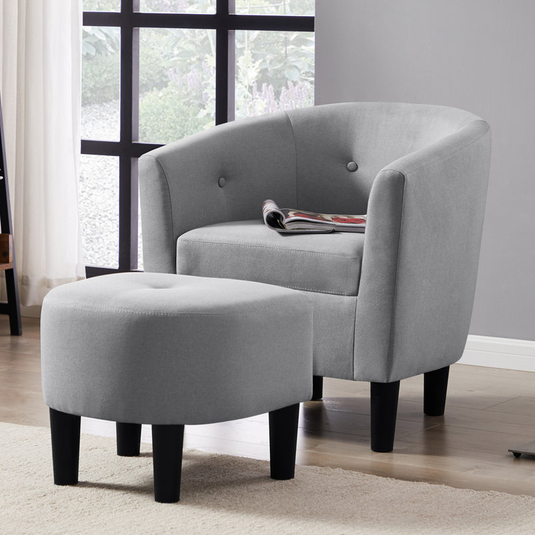 A gray upholstered chair with button detailing, accompanied by a matching ottoman, both featuring dark wood legs.