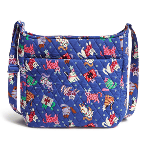 A quilted Vera Bradley XL Crossbody bag with a vibrant blue background featuring colorful cats in various playful poses wearing winter clothing. It has an adjustable strap and multiple exterior pockets.