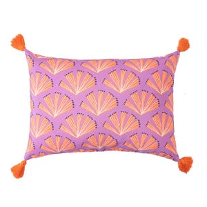 A rectangular pillow with a purple background features an orange and white geometric fan pattern, accented by orange tassels at each corner.