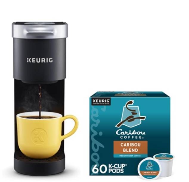 A black Keurig K-Mini single-serve coffee maker is brewing coffee into a yellow mug, next to a box of 60 Caribou Coffee K-Cup pods.