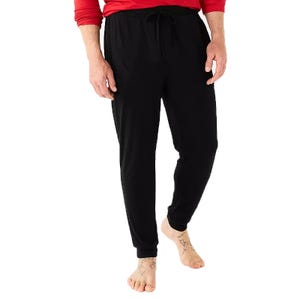 Black jogger pants with an elastic waistband and drawstring, paired with a red long-sleeve shirt, worn barefoot.
