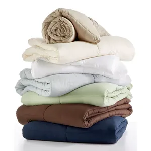 Stack of rolled and folded comforters in various colors.