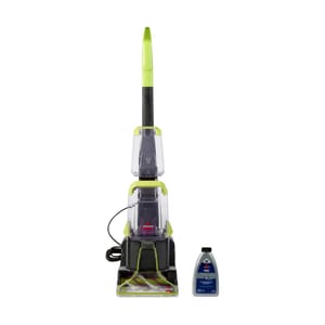 A green and black upright carpet cleaner with an attached cleaning solution bottle.