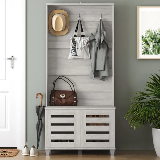 Gray hallway organizer with hooks for hats, bags, and coats, a storage bench with slatted doors, and space for shoes and umbrellas. Includes a potted plant, a framed plant print, and a nearby doormat.
