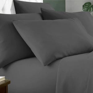 A set of six dark grey bamboo sheets, including a fitted sheet, a flat sheet, and four pillowcases, arranged on a bed.