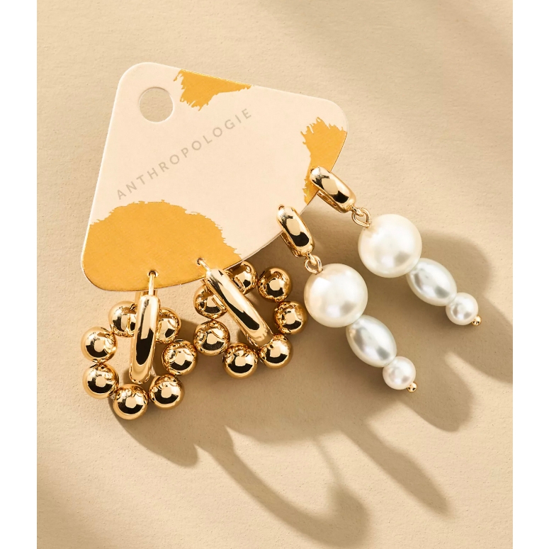 A pair of Anthropologie earrings featuring one set with gold beads arranged in a circular pattern and another set with a trio of pearls in varying sizes.
