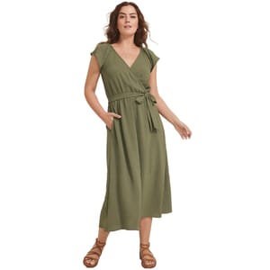 A woman is wearing an olive green wrap dress with short sleeves, a tie belt at the waist, and paired with brown strappy sandals.
