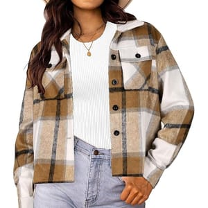 A woman wearing a brown and white plaid shacket over a white ribbed top and light blue jeans, accessorized with a gold necklace and wide-brimmed hat.