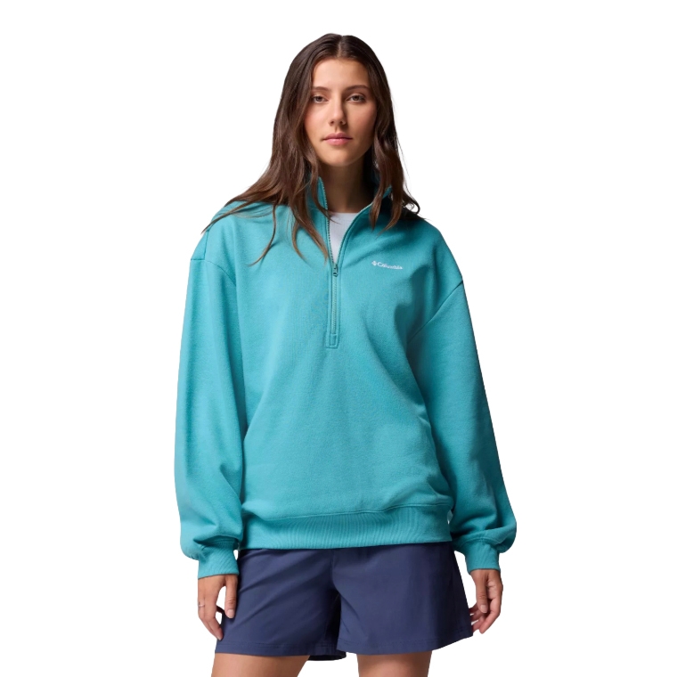 A woman is wearing a turquoise Columbia quarter-zip fleece pullover and navy blue shorts.