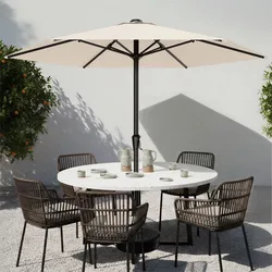 Outdoor patio setup with a white umbrella, round white table, and six brown wicker chairs. Tableware includes cups and pitchers.