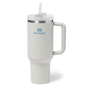 A white Stanley travel mug with a handle, straw lid, and an engraved logo.