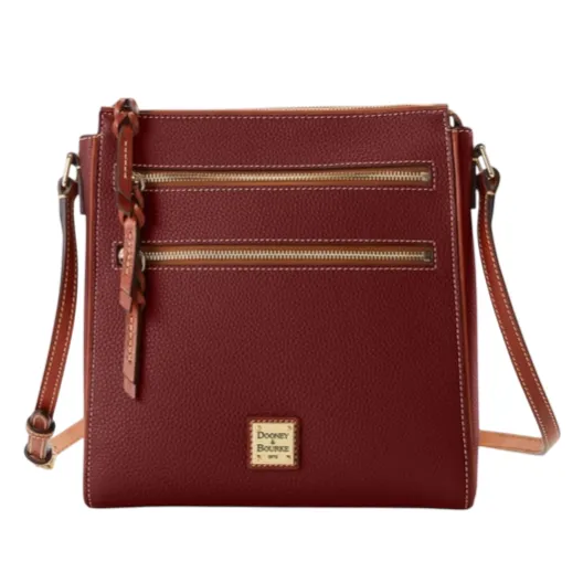 A burgundy crossbody bag with two front zippered pockets, a braided leather zipper pull, and an adjustable shoulder strap. The bag has a gold Dooney & Bourke logo plaque.