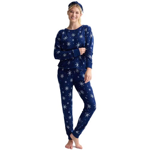 A person is wearing a navy blue pajama set with snowflake patterns, including a long-sleeve top, pants, and a matching headband.