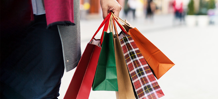Hand holds holiday shopping bags on an autumn day.