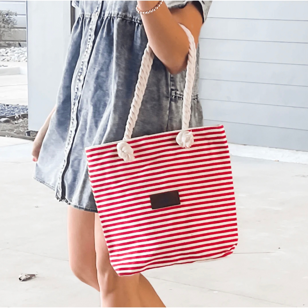 Red and white striped canvas tote bag with sturdy rope handles tied in knots, featuring a dark rectangular patch on the front; measures 14 inches in height.