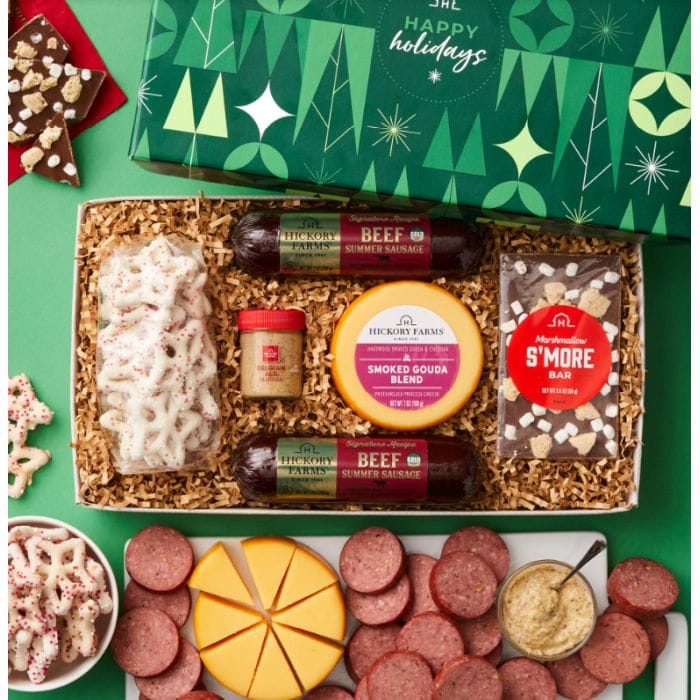 Gift box featuring beef summer sausage, smoked Gouda cheese, mustard, a marshmallow s'more bar, yogurt-covered pretzels, and holiday-themed packaging.