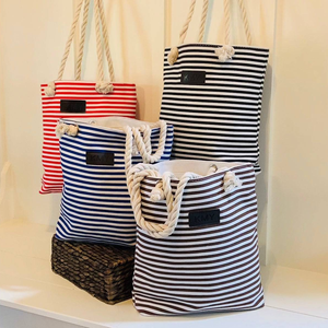 Three striped tote bags with rope handles and personalized black tags displaying different initials.