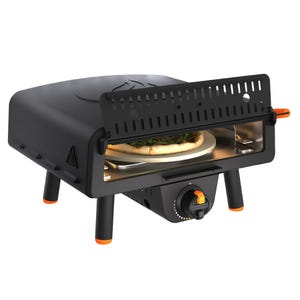 A compact Blackstone Tabletop Pizza Oven with a black design and orange accents, featuring a pizza inside. It has a front panel with vents, adjustable temperature control, and four sturdy legs for stability.