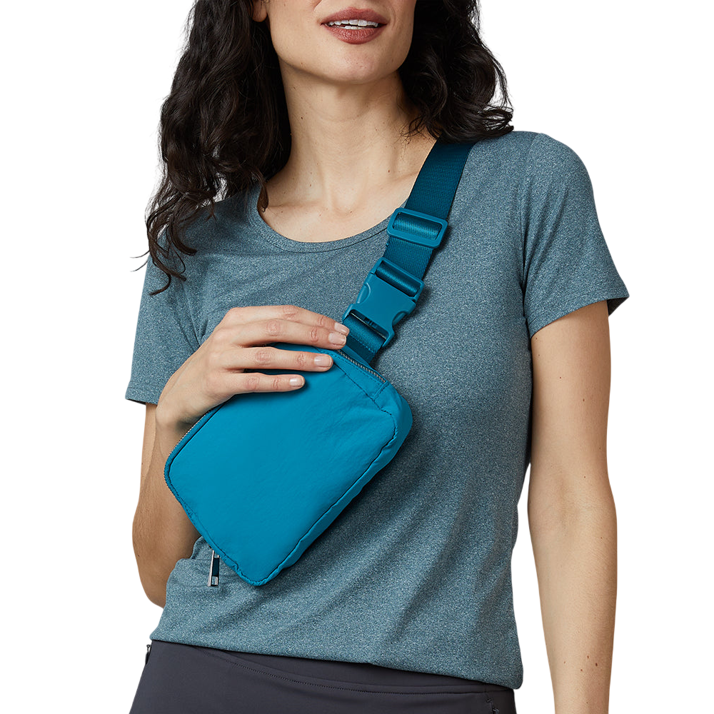 A person wearing a blue-gray t-shirt with a small, bright blue crossbody bag secured with an adjustable strap across their chest.