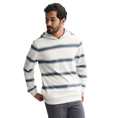 A man models a light gray hoodie with dark blue horizontal stripes, paired with charcoal gray pants.