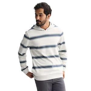 A man models a light gray hoodie with dark blue horizontal stripes, paired with charcoal gray pants.