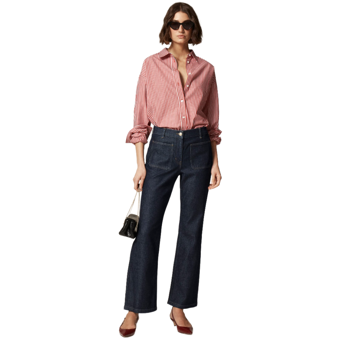 Woman wearing a red striped shirt, dark blue wide-leg jeans, red pointed flats, and sunglasses, holding a small handbag.