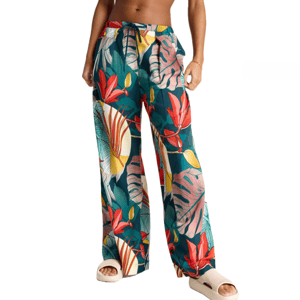 Tropical print swim cover-up pants featuring a drawstring waist with green, red, yellow, and white leaf designs. Paired with beige slide sandals.