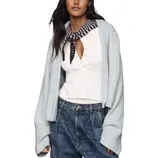 A person wears a white buttoned top and dark jeans with a light gray cardigan draped over their shoulders. A striped scarf is tied around the neck.