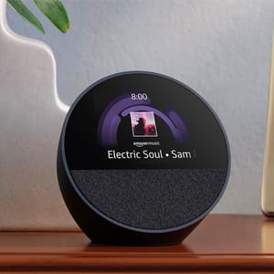A spherical smart display with a clock interface showing the time and a music track playing on Amazon Music.