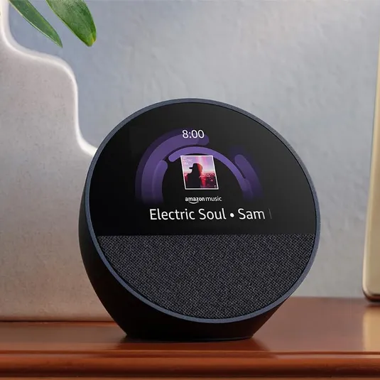 A spherical smart display with a clock interface showing the time and a music track playing on Amazon Music.