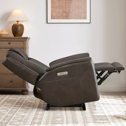 A brown reclining chair is shown in a living room setting, partially reclined next to a wooden dresser and a table lamp. A patterned rug is on the floor.