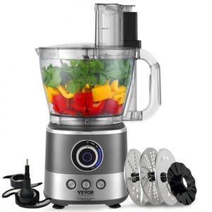 Food processor with various attachments and sliced vegetables inside the bowl.