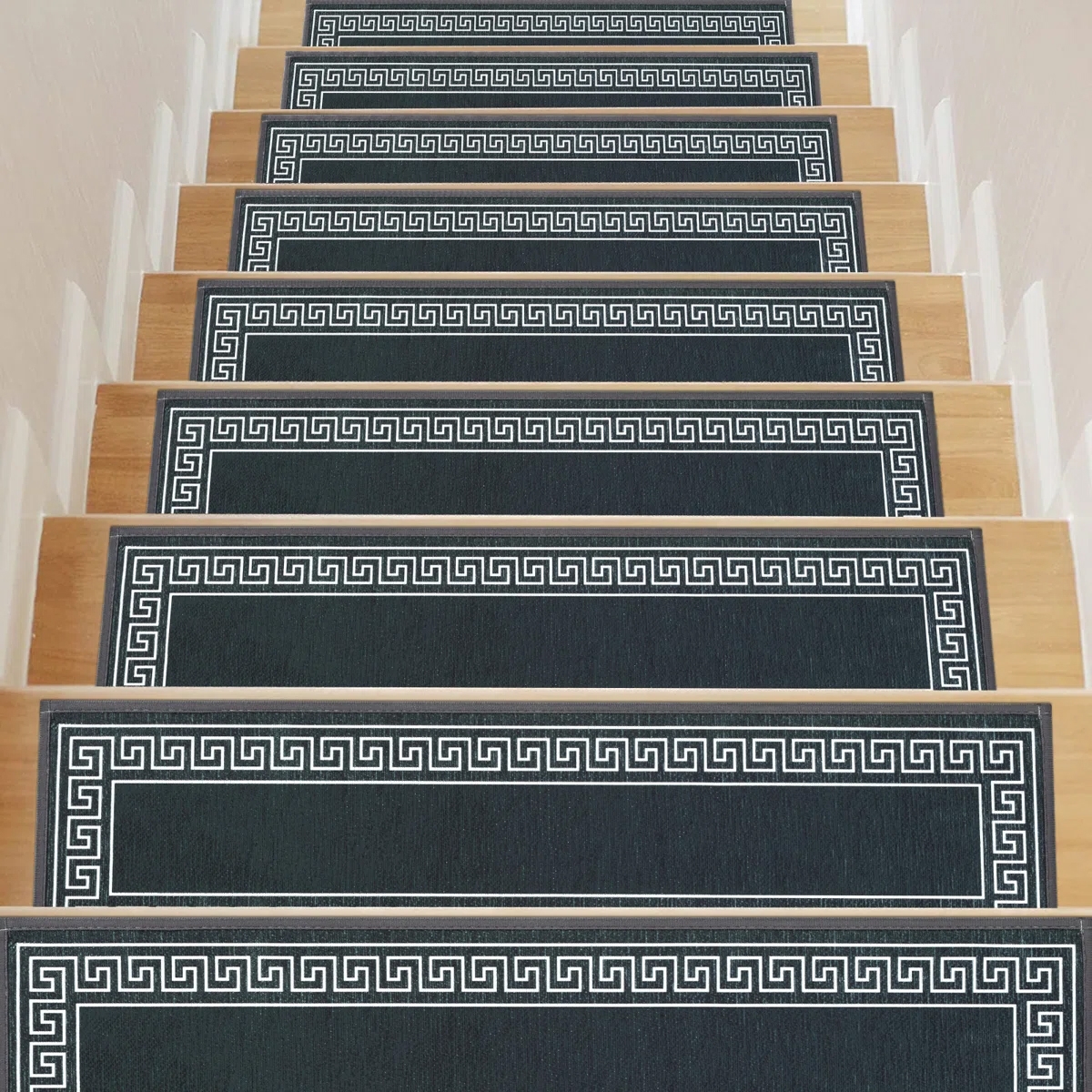 Stair treads with a Greek key pattern on dark fabric, set on light wooden steps.