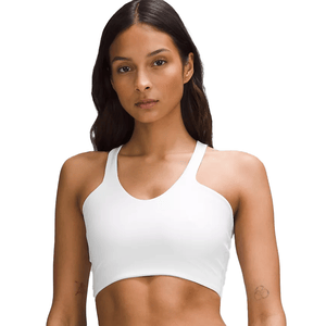 A woman is wearing a white sports bra with thin shoulder straps. She has long hair and a tattoo on her arm.