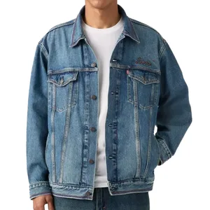 A person is wearing a blue denim jacket with button closures, front pockets, and a small embroidered logo on the chest, over a white T-shirt.