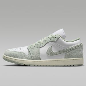 A green and white Nike Air Jordan 1 Low sneaker with a suede texture on the upper.