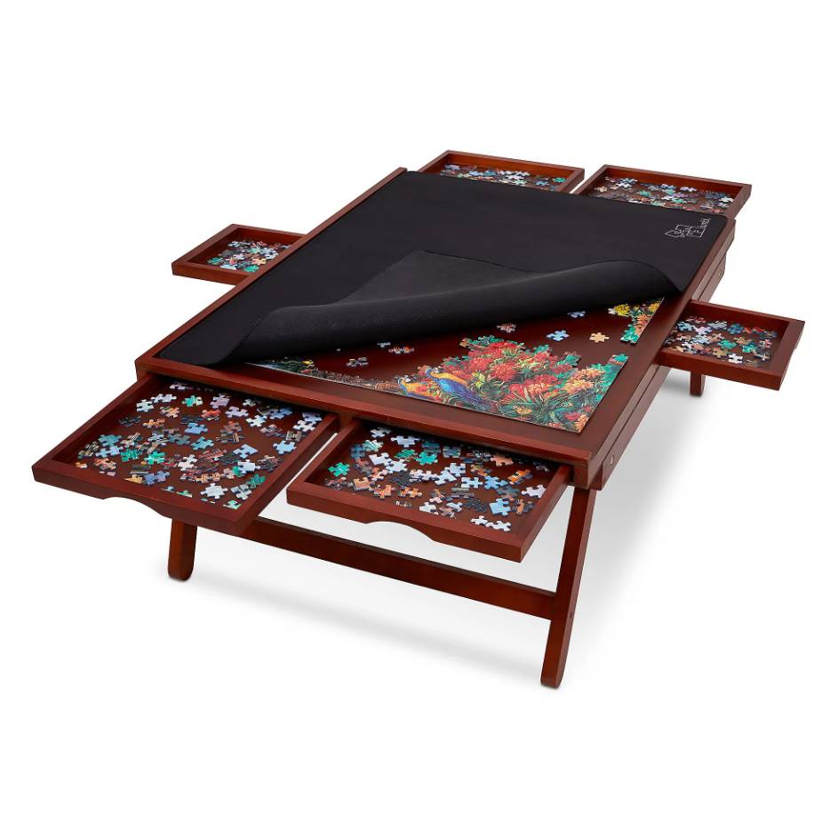 A wooden puzzle table with a central puzzle area, covered partially by a black mat, and six side drawers holding puzzle pieces.