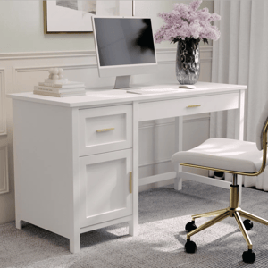 A white desk with a computer, keyboard, mouse, and a vase of purple flowers sits on a gray carpet. The desk features gold handles and is paired with a white chair with gold accents.