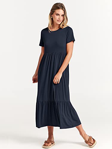 A woman models a navy blue, short-sleeve maxi dress with a round neckline, gathered waist, and a ruffled hem, paired with tan sandals.