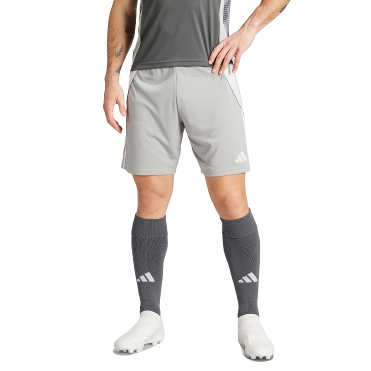 A person is wearing light gray athletic shorts and dark gray knee-high socks with white cleats. The outfit includes a dark gray top, and there are visible logos on the shorts and socks, suggesting a sports apparel brand.