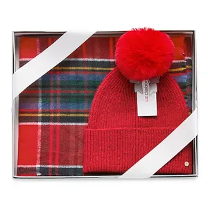 Red knit beanie with a pom-pom and a red plaid scarf, packaged in a gift box.