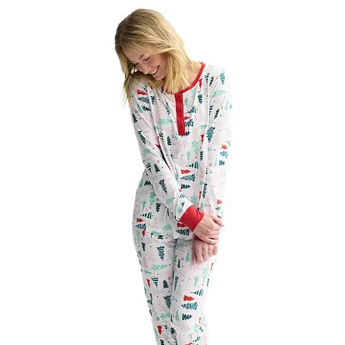 Woman wearing a festive pajama set with a Christmas tree pattern, featuring red cuffs and neckline.