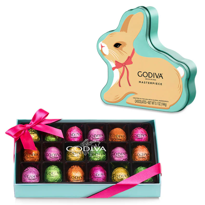 A Godiva bunny-shaped tin and a box of assorted chocolate truffles wrapped in colorful foil with a pink ribbon.