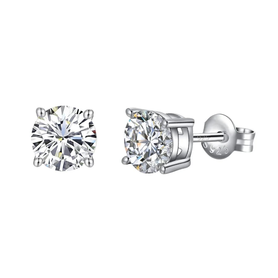 A pair of round-cut silver stud earrings with clear gemstones, set in four prong settings and featuring a 925 sterling silver marking on the back.
