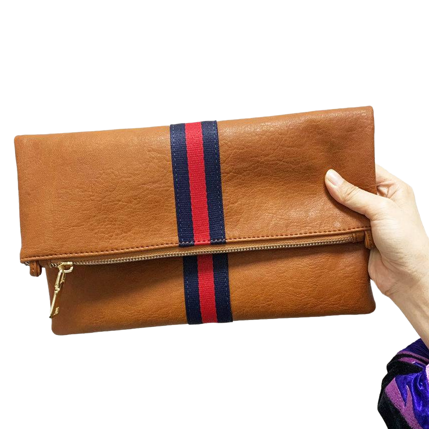 Brown fold-over clutch with a horizontal red and blue stripe, featuring a zipper closure and gold accents, held by a hand.
