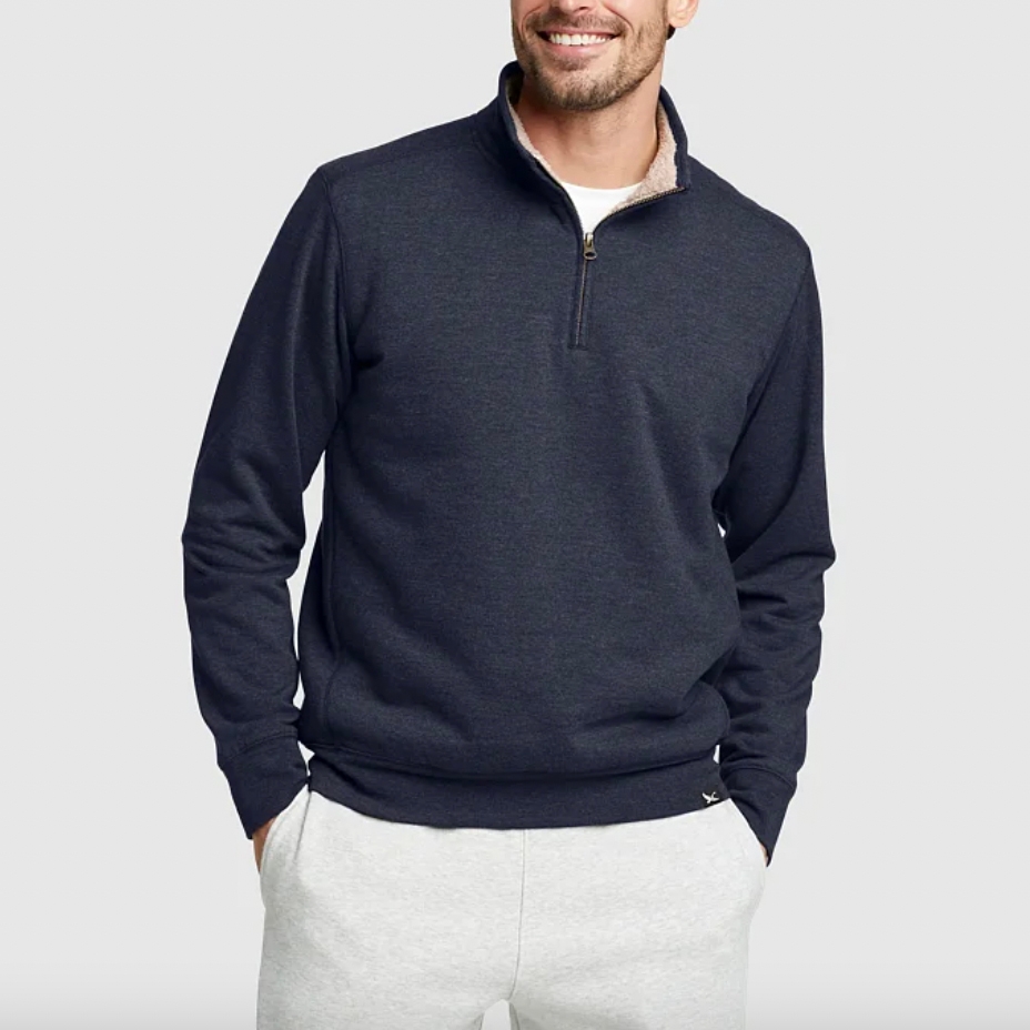 A man wearing a dark blue pullover with a half-zip collar and light gray sweatpants.