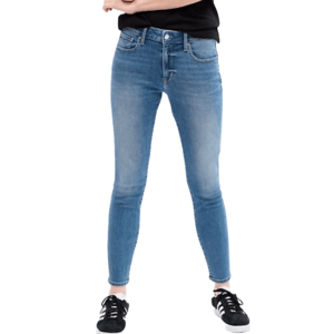Blue mid-rise legging jeans with a slightly faded finish, featuring front and back pockets. Paired with black sneakers and a black top.