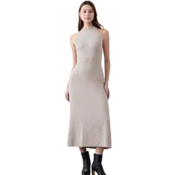 A woman is wearing a sleeveless, beige ribbed knit midi dress paired with black ankle boots featuring a block heel.